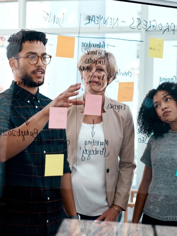 Colleagues looking at sticky notes on a board
